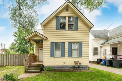 a yellow house with blue windows and a fence at Just Like Home in Cleveland