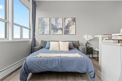 a bedroom with a bed with blue sheets and a window at 1BR • City Views • Queen + SofaBed • WiFi & 2 TVs in Cleveland