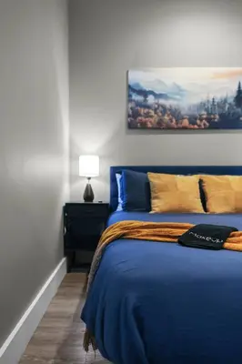 a bedroom with a blue bed with a painting on the wall at 1BR • City Views • Queen + SofaBed • WiFi & 2 TVs in Cleveland