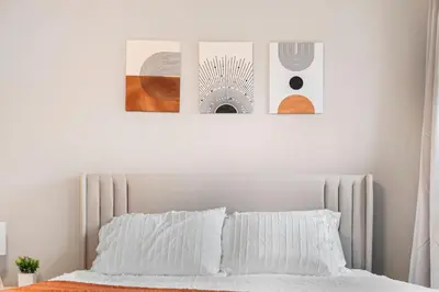 a white bedroom with two pictures above a bed at Spacious Home Near Hospitals with Office & Game Room in Cleveland Heights