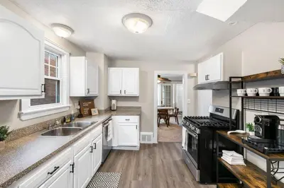 a kitchen with white cabinets and a sink and a stove at Spacious Home Near Hospitals with Office & Game Room in Cleveland Heights