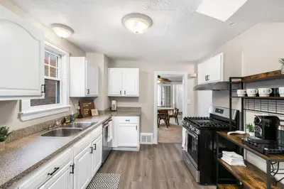 a kitchen with white cabinets and a sink and a stove at Spacious Home Near Hospitals with Office & Game Room in Cleveland Heights
