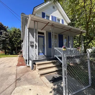 a white house with a porch and a fence at Urban OASIS Inspired by the 80s Unit 1 in Cleveland