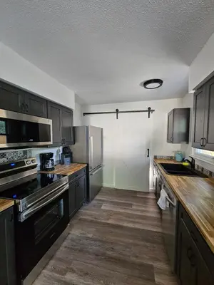 a kitchen with black appliances and wooden floors at Cozy 3BR Cottage Near Headlands in Mentor