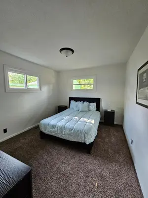 a bedroom with a bed and two windows at Cozy 3BR Cottage Near Headlands in Mentor