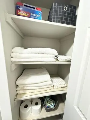 a closet with white towels and rolls of toilet paper at Comfortable and Calm Stay in Columbus in Columbus