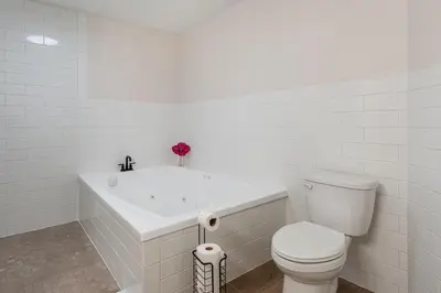 a white bathroom with a toilet and a bath tub at The Gathering Haus in Dalton