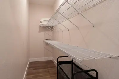a walk in closet with a white wall and a shelf at The Gathering Haus in Dalton