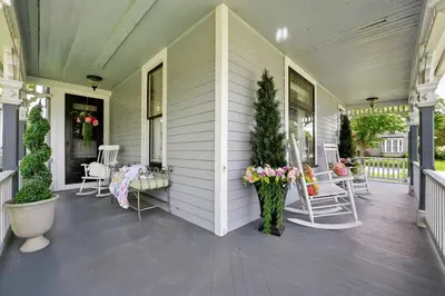 a porch of a house with chairs and flowers at The Victorian House in Canfield