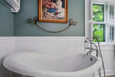 a white bath tub in a bathroom with a painting at The Victorian House in Canfield