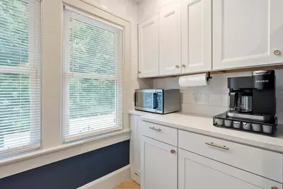 a kitchen with white cabinets and a microwave and two windows at Close to OSU Rooftop Patio Grill & Outdoor TV in Columbus