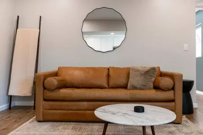 a living room with a brown couch and a mirror at Clintonville Brand New Apartment in Columbus