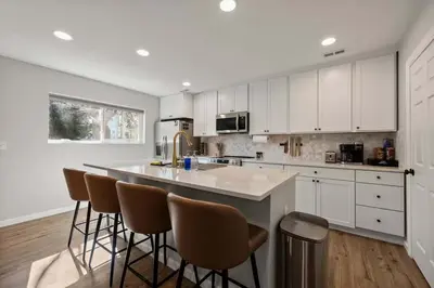 a kitchen with white cabinets and a island with bar stools at Clintonville Brand New Apartment in Columbus