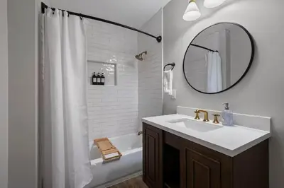 a white bathroom with a sink and a mirror at Clintonville Brand New Apartment in Columbus