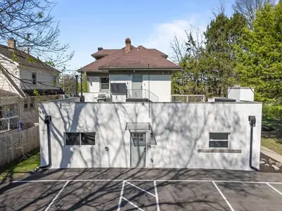 a white house with a parking lot in front of it at Clintonville Brand New Apartment in Columbus