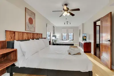 a bedroom with a large white bed with a ceiling fan at The Meadow Adventure in Columbus