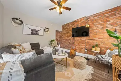 a living room with a couch and a brick wall at Sophisticated Boho Condo Walkable Columbus in Columbus