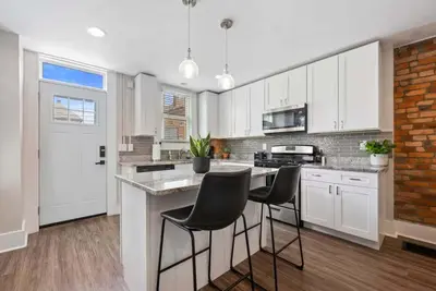 a kitchen with white cabinets and black chairs at Sophisticated Boho Condo Walkable Columbus in Columbus