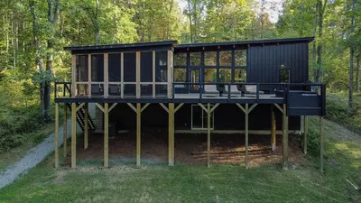 a black house on wooden posts in the woods at The Hollow House in McArthur