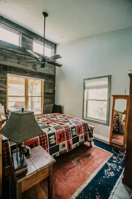 a bedroom with a bed and a table and windows at The Honey Hut Think of On Golden Pond in Mount Sterling