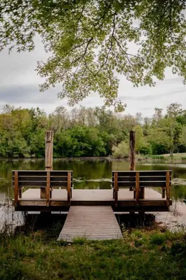 two benches sitting on a dock over a lake at The Honey Hut Think of On Golden Pond in Mount Sterling
