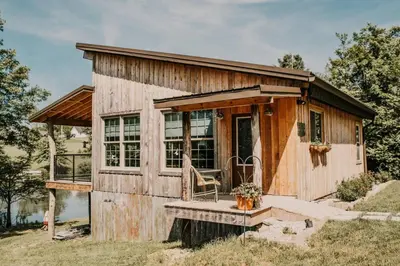 a small wooden house with a porch and a chair at The Honey Hut Think of On Golden Pond in Mount Sterling