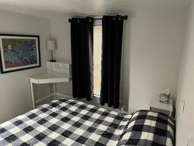 a bedroom with a bed with black curtains and a window at Gem 1 Downtown Willoughby Historic District in Willoughby
