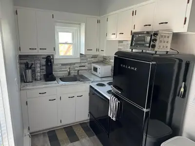 a kitchen with white cabinets and a black refrigerator at Downtown Willoughby Historic District Gem 3 in Willoughby