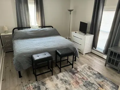 a bedroom with a bed with two chairs and a television at Downtown Willoughby Historic District Gem 3 in Willoughby