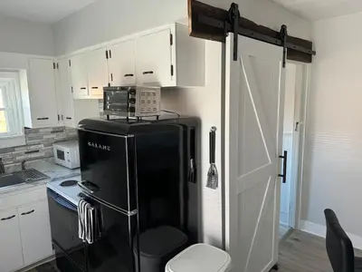 a kitchen with a black refrigerator and white cabinets at Downtown Willoughby Historic District Gem 3 in Willoughby