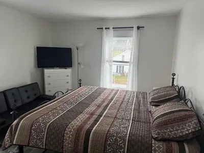a bedroom with a bed and a tv and a window at Downtown Willoughby historical district Gem 4 in Willoughby