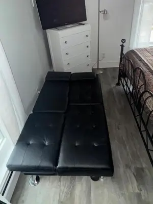 a black bench in a bedroom with a bed and a dresser at Downtown Willoughby historical district Gem 4 in Willoughby