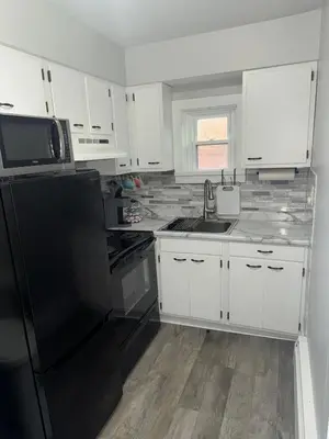 a kitchen with white cabinets and a black refrigerator at Downtown Willoughby historical district Gem 4 in Willoughby