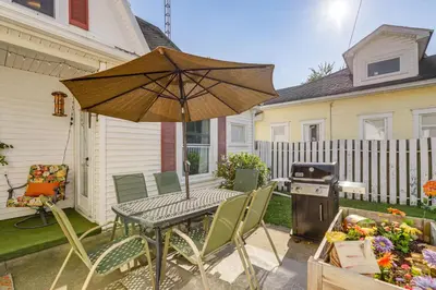 a patio with a table with an umbrella and a grill at Walkable Group Getaway with Bikes in West Liberty! in West Liberty