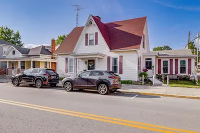 two cars parked in a parking lot in front of a house at Walkable Group Getaway with Bikes in West Liberty! in West Liberty