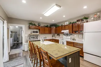 a kitchen with wooden cabinets and a large kitchen island at Walkable Group Getaway with Bikes in West Liberty! in West Liberty