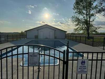 a swimming pool with a building in the background at Country Cornerstone Retreat Upstairs Apartment with Hot Tub, Jetted Tub, Sauna, Massage Chair, BBQ in Hillsboro