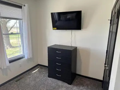 a room with a television on a wall with a dresser at Country Cornerstone Retreat Upstairs Apartment with Hot Tub, Jetted Tub, Sauna, Massage Chair, BBQ in Hillsboro