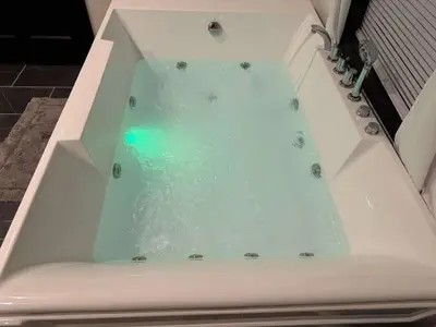 a bath tub filled with blue water in a bathroom at Country Cornerstone Retreat Upstairs Apartment with Hot Tub, Jetted Tub, Sauna, Massage Chair, BBQ in Hillsboro