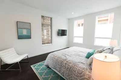 a white bedroom with a bed and a chair at Unique contemporary 1600ft2 2BR 3BA apt OTR in Cincinnati