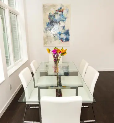 a glass table with white chairs and a vase of flowers at Unique contemporary 1600ft2 2BR 3BA apt OTR in Cincinnati