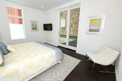 a bedroom with a bed and a chair and a window at Unique contemporary 1600ft2 2BR 3BA apt OTR in Cincinnati