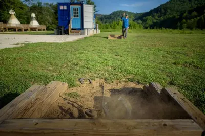a man standing in a field with a fire pit at Furnished Glamping Tent/River Access/2 Queen Beds in Stanton