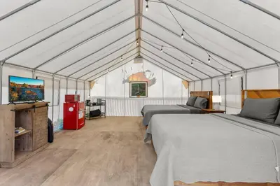 a bedroom with two beds and a tv in a tent at Furnished Glamping Tent/River Access/2 Queen Beds in Stanton