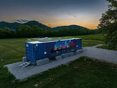 a container with graffiti on it sitting in a field at Furnished Glamping Tent/Red River Access/King Bed in Stanton