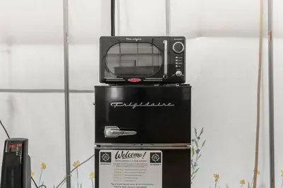 a microwave sitting on top of a refrigerator at Furnished Glamping Tent/Red River Access/King Bed in Stanton