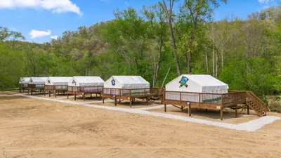 a row of huts in a row on a dirt field at Furnished Glamping Tent/Red River Access/King Bed in Stanton