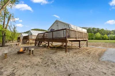 a playground with a house and a fire in the sand at Furnished Glamping Tent/River Access/2 Queen Beds in Stanton