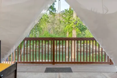 a wooden balcony with a view of a forest at Furnished Glamping Tent/Red River Access/King Bed in Stanton