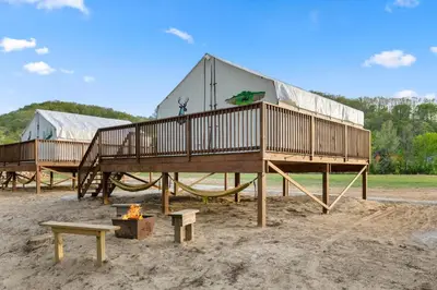 a house with a fire in front of a building at Furnished Glamping Tent/Red River Access/King Bed in Stanton